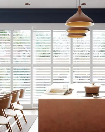 White tracked shutters in modern and stylish navy kitchen