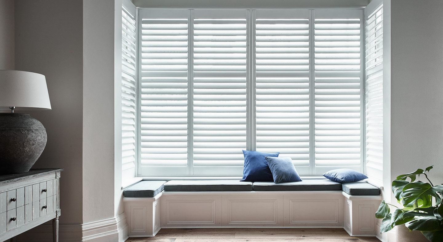 Lounge White window shutters with window seat and blue pillows