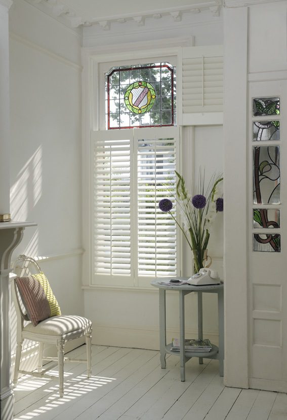 Stained glass window with white tier on tier shutters