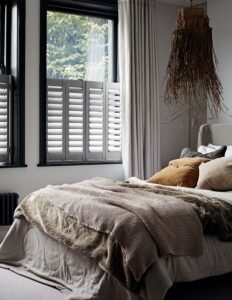 Cafe style window shutters with curtains in bedroom