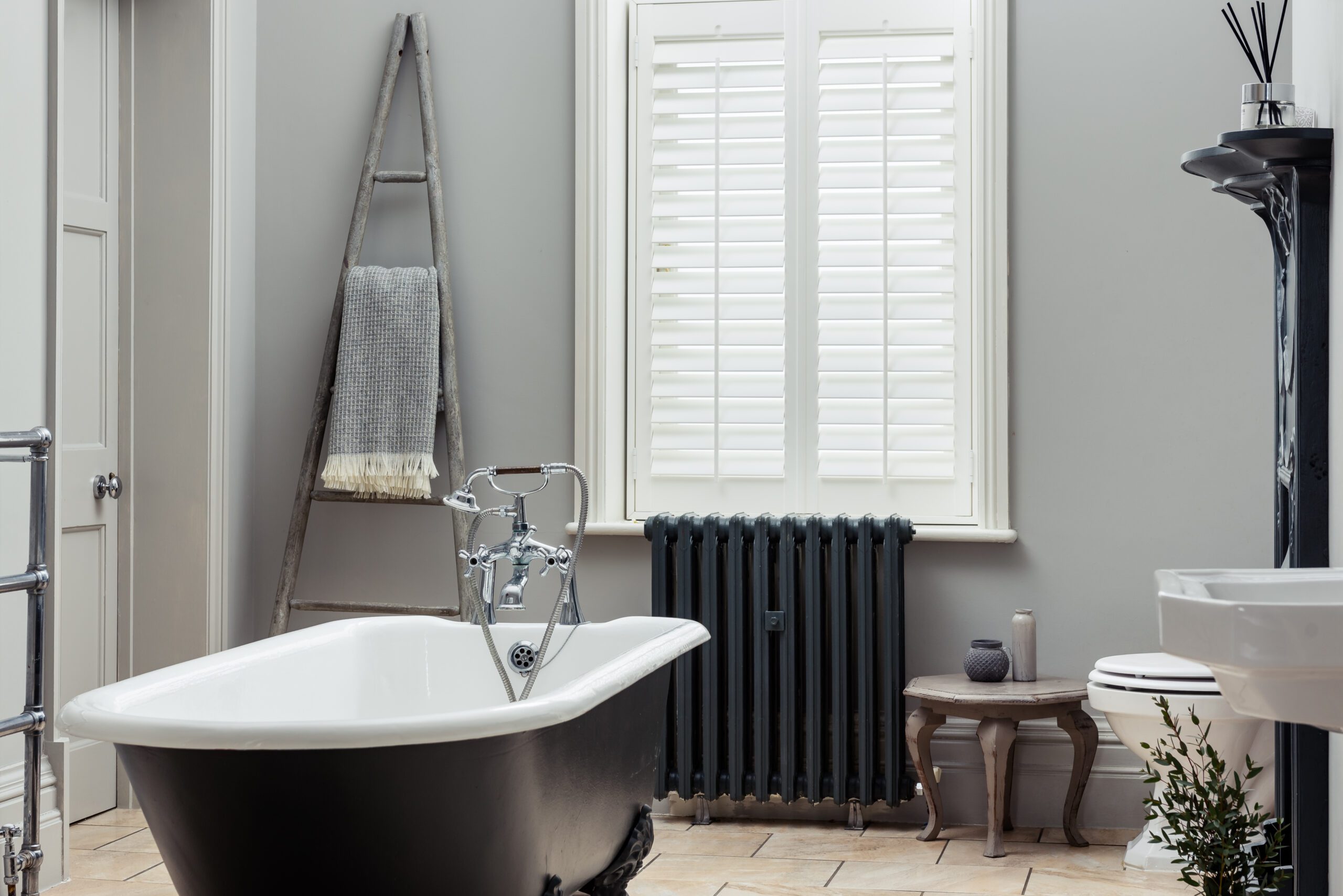 White bathroom shutters in a room with a black and white bathtub