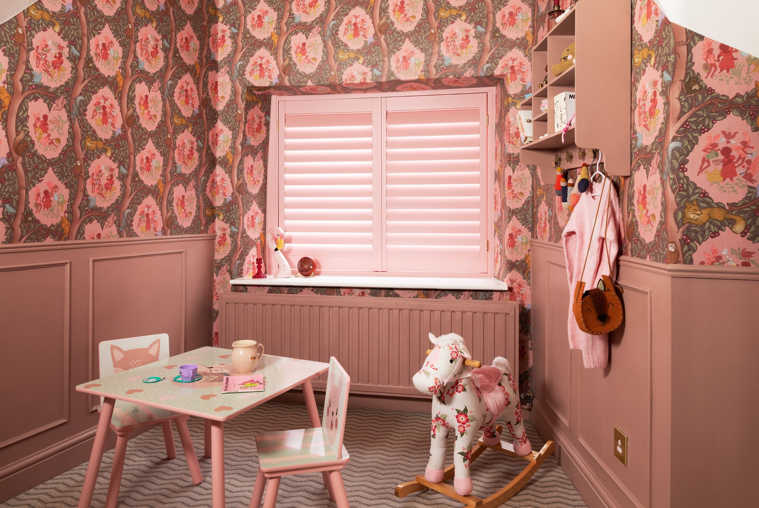light pink shutters in small play room with rocking horse and small children's table and chairs in front of the window
