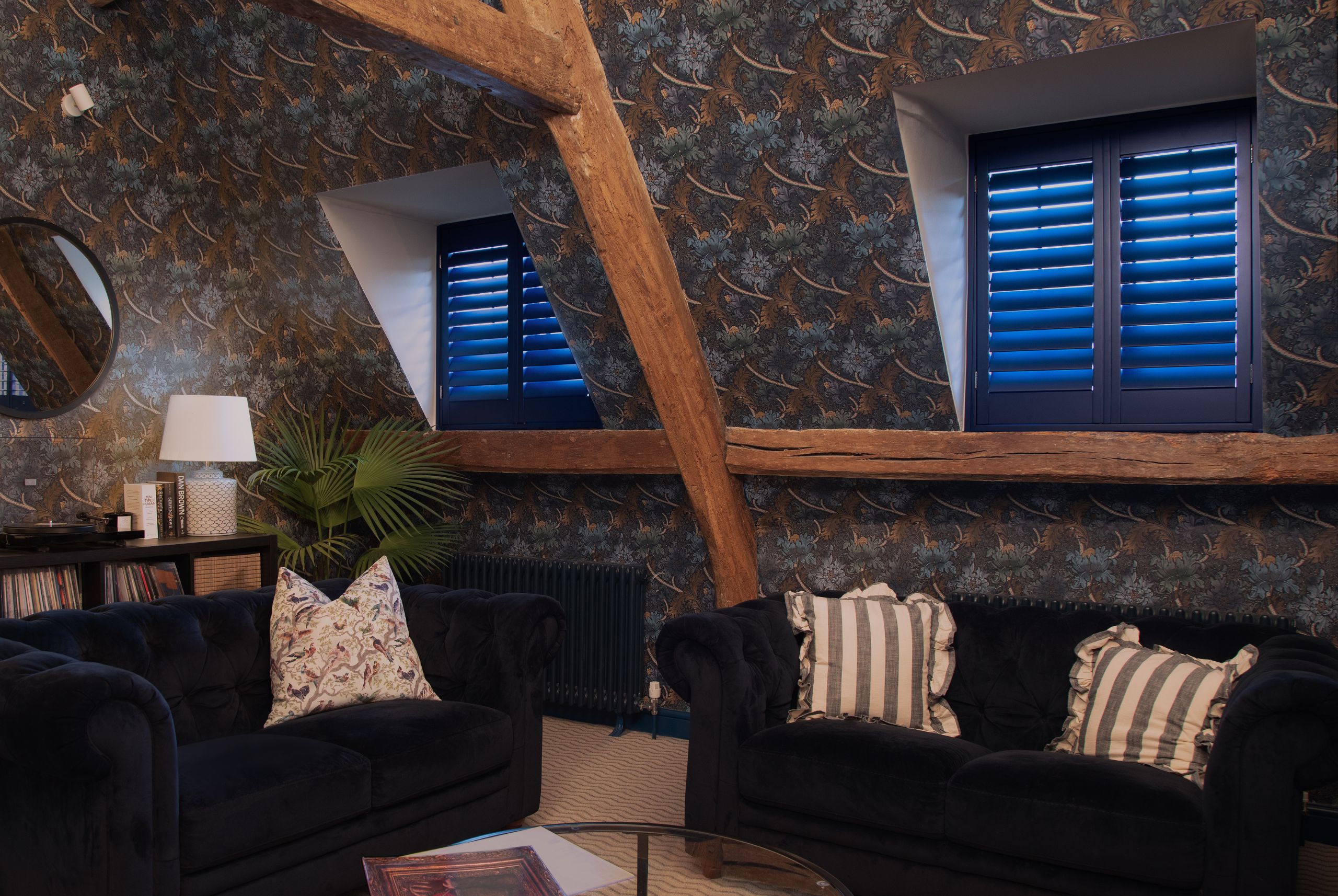 dark green shutters with dark sofas underneath the windows