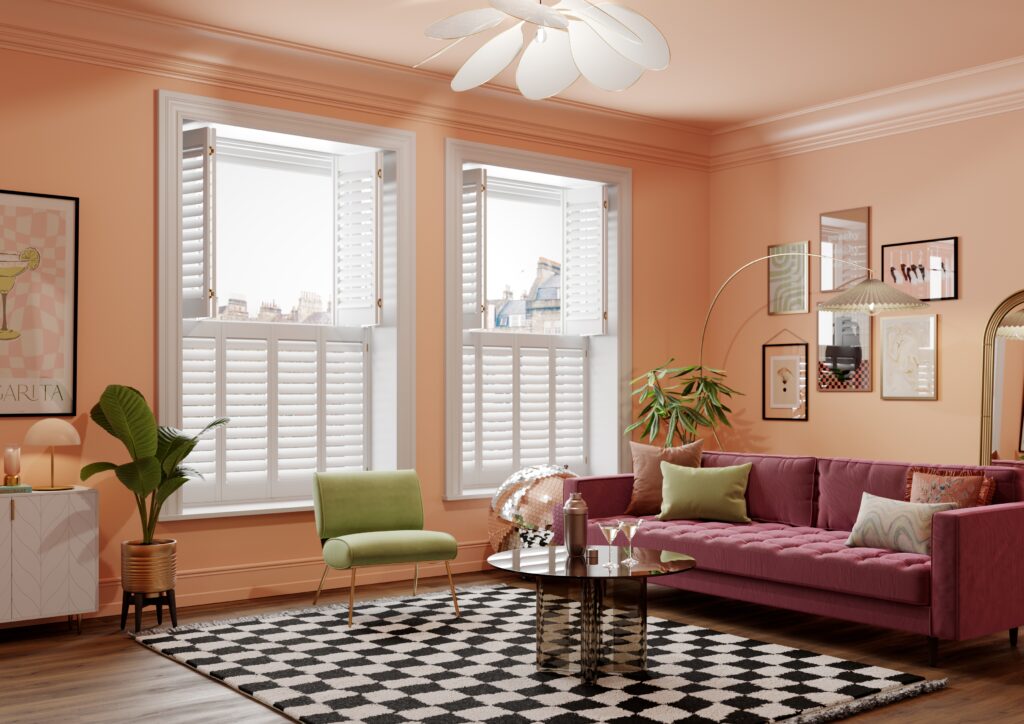 White tier on tier shutters with top panels open in living room with pink sofa, green chair and checked rug